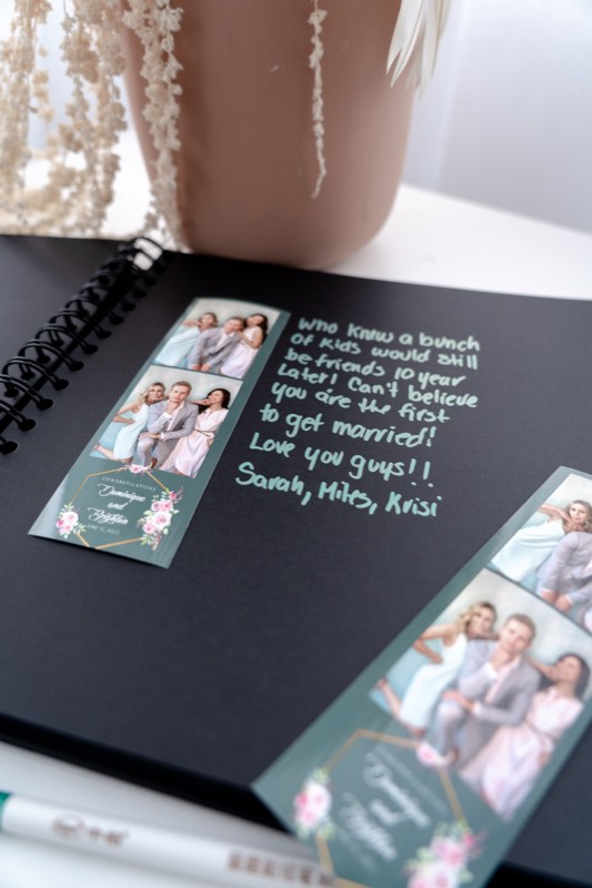 Photo strips taped into a black guest book beside a handwritten note from guests